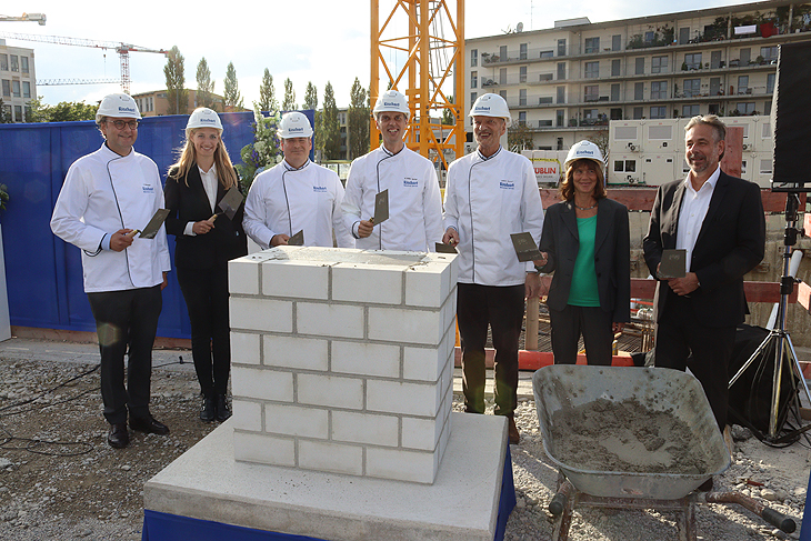 Christian Merzenich, Produktionsleiter Max Rischart’s Backhaus KG; Nadja Heckl, Verkaufsleitung Max Rischart’s Backhaus KG; Michael Scheyerl, Leiter Verwaltung und Controlling Max Rischart’s Backhaus KG; Magnus Müller-Rischart, Inhaber und Geschäftsführer Max Rischart’s Backhaus KG; Gerhard Müller-Rischart; Sibylle Stöhr, Vorsitzende des Bezirksausschusses 8 Schwanthalerhöhe; Daniel Hock, Architekt Kiessler Architekten GmbH vor dem Grundstein mit Zeitkapsel der neuen Rischart Unternehmenszentrale (©Foto: Martin Schmitz)